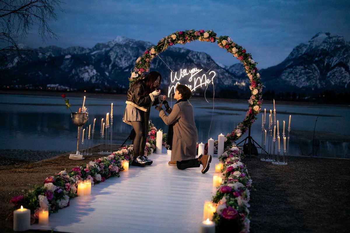 Romantic marriage proposal at alpine lake in winter – flower heart decoration with candles