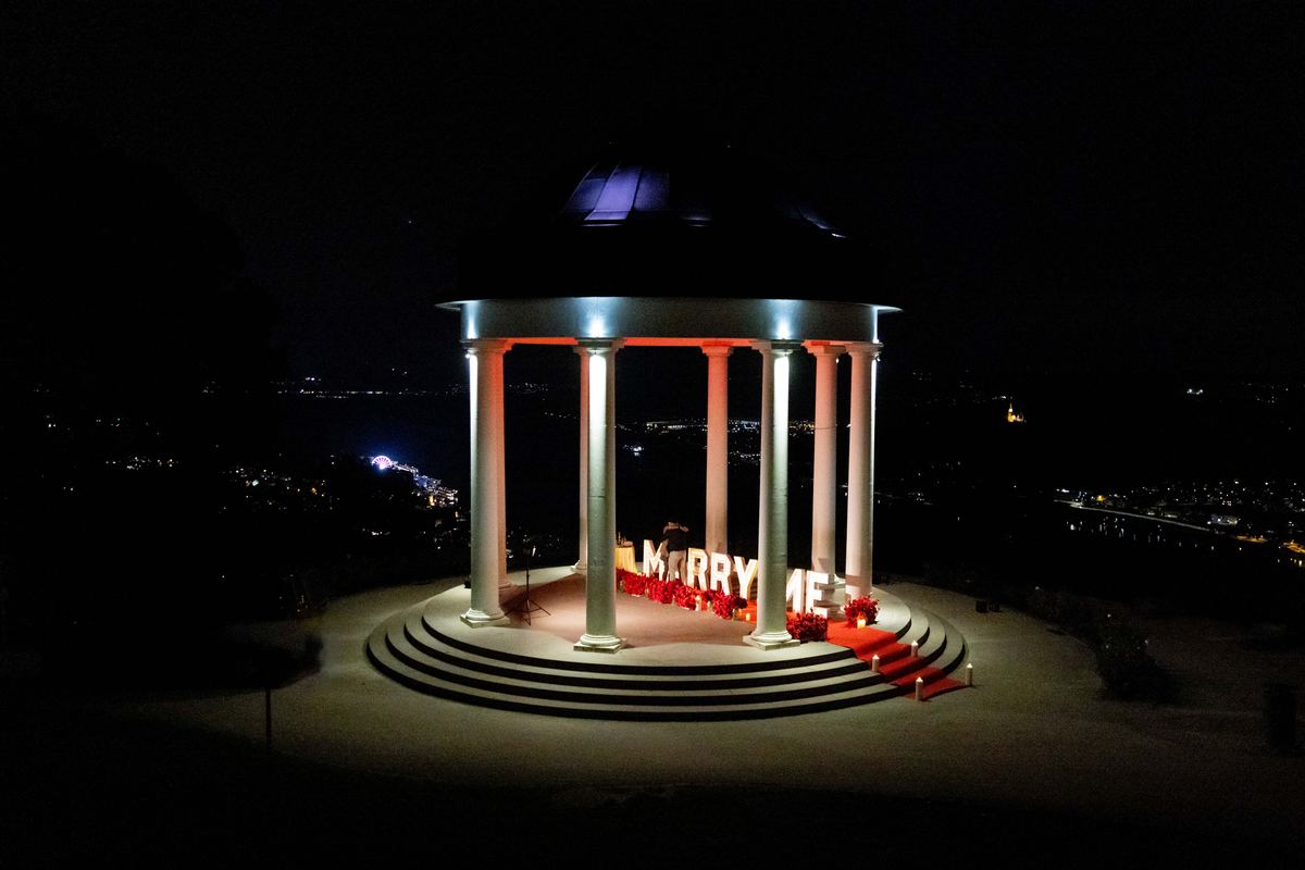 Romantic marriage proposal at ancient temple at night with MARRY ME illumination