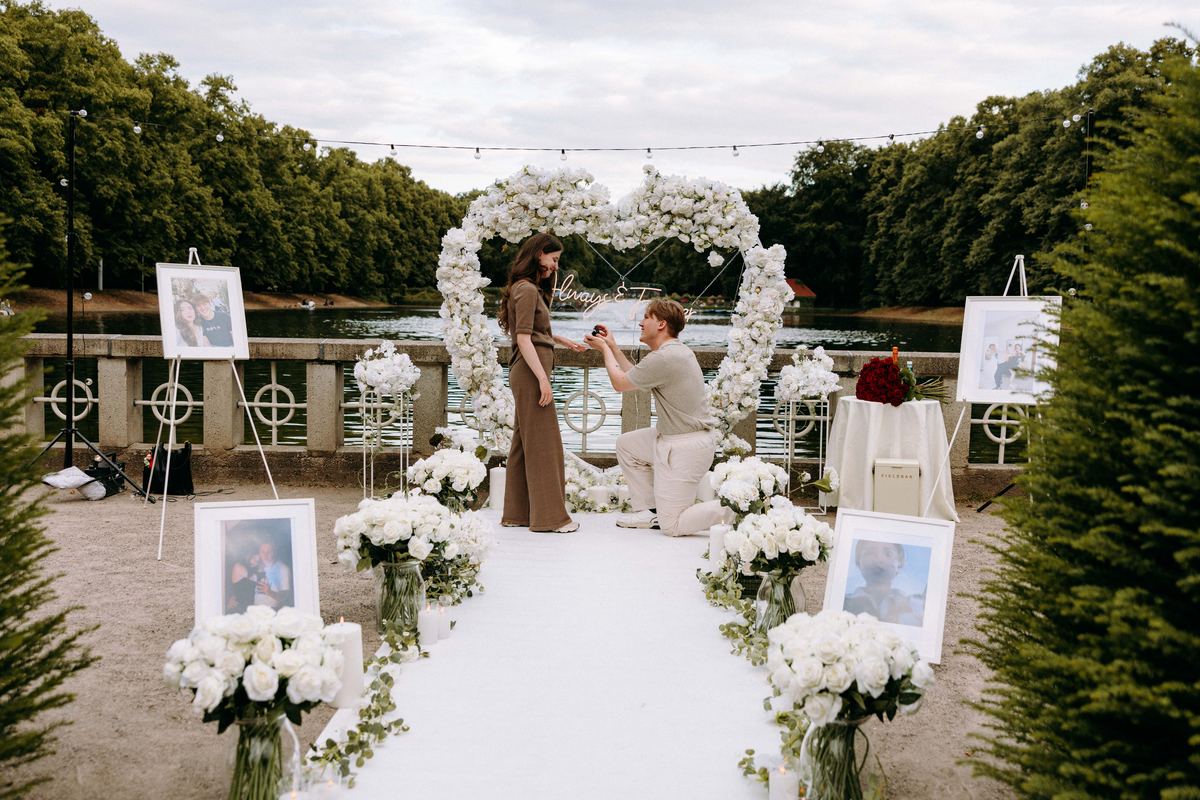 Marriage proposal in park with white flower heart, lake view and photo arrangement