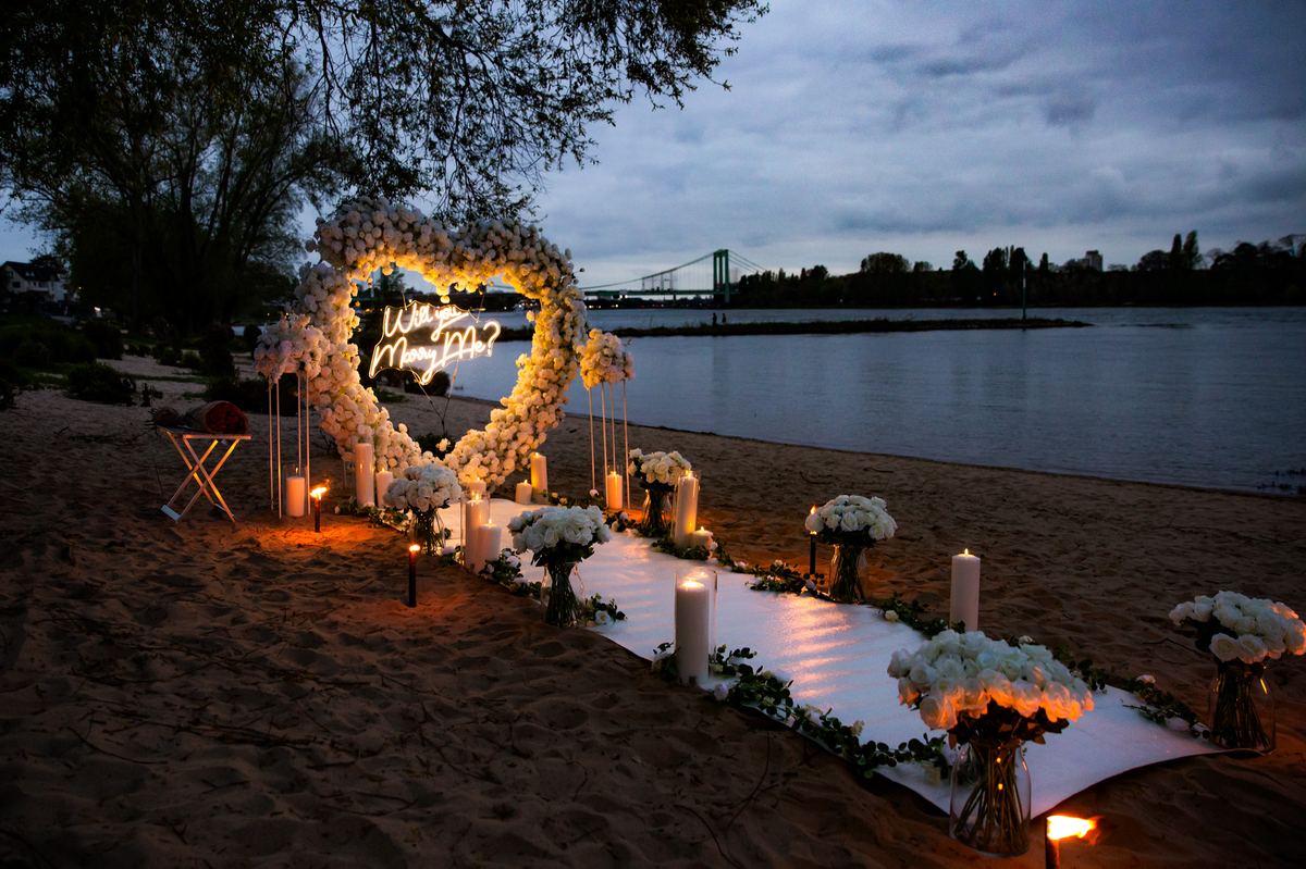 Marriage proposal in Cologne – Rhine riverside beach with white heart at night