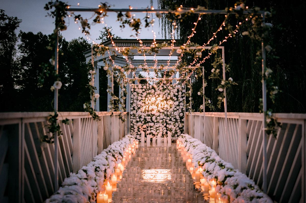 Marriage proposal in Frankfurt Palmengarten – bridge decorated with flower wall and fairy lights