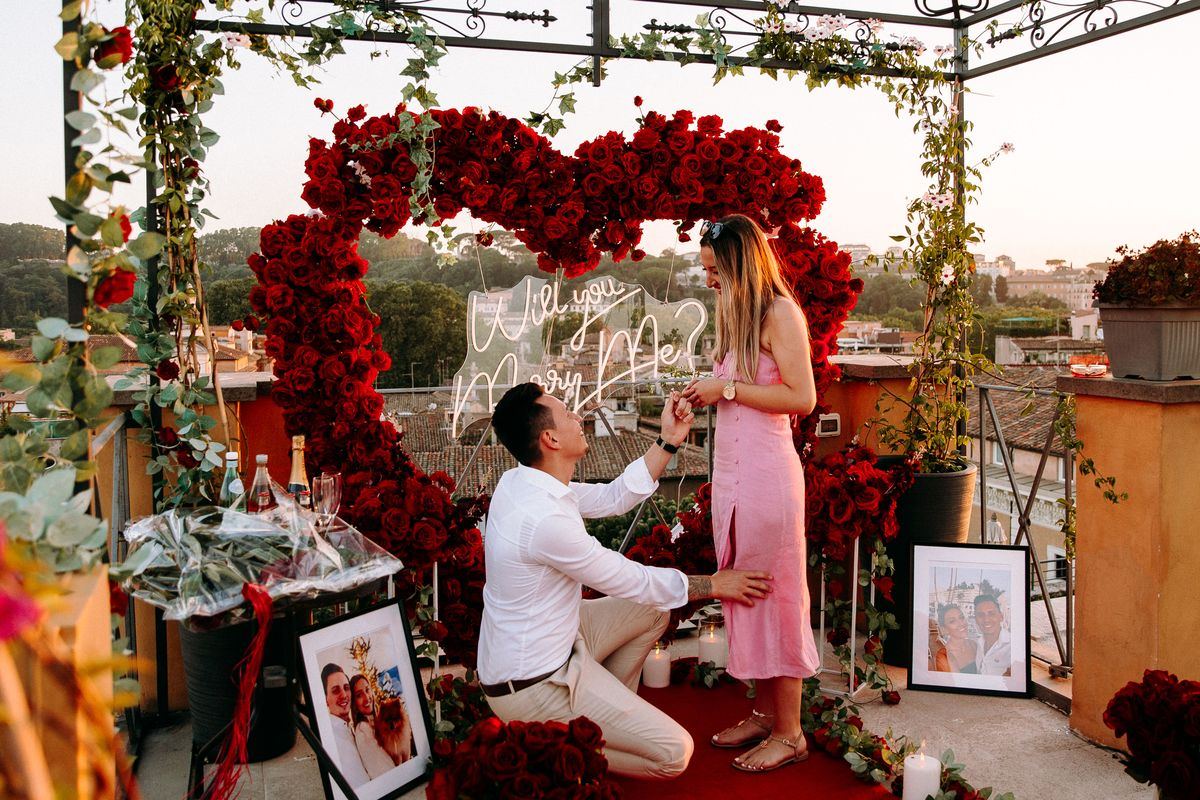 Marriage proposal in Rome – rooftop with red heart and neon sign, man kneeling with ring